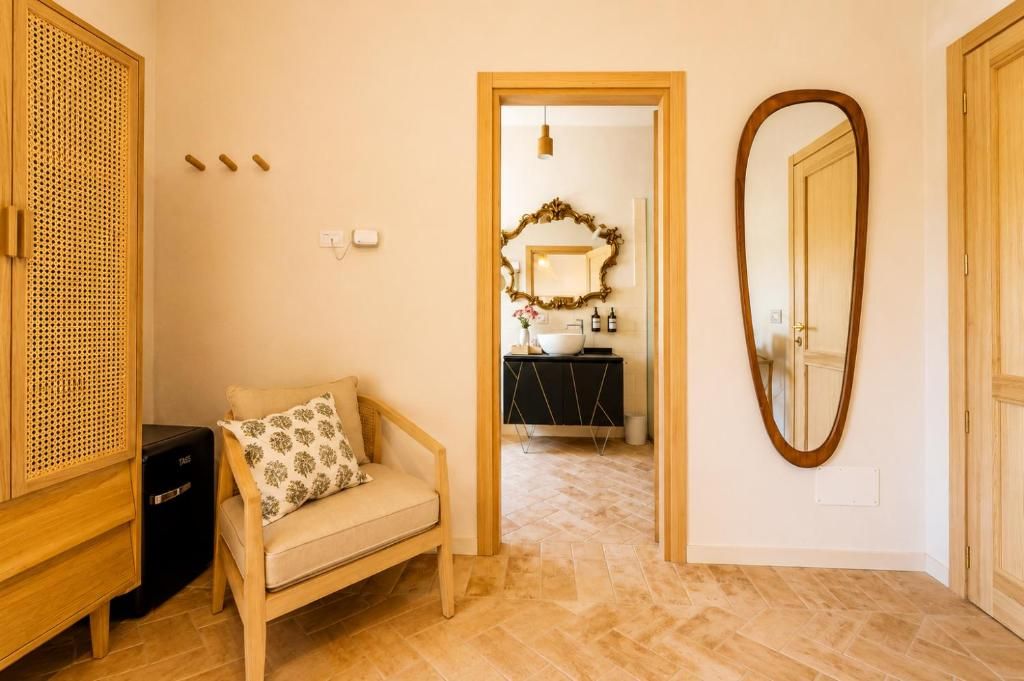 Un couloir avec un banc en bois, un miroir et une porte donnant sur une salle de bain.
