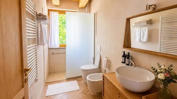 A bathroom with a wooden vanity, a large sink, a toilet, and a shower area.