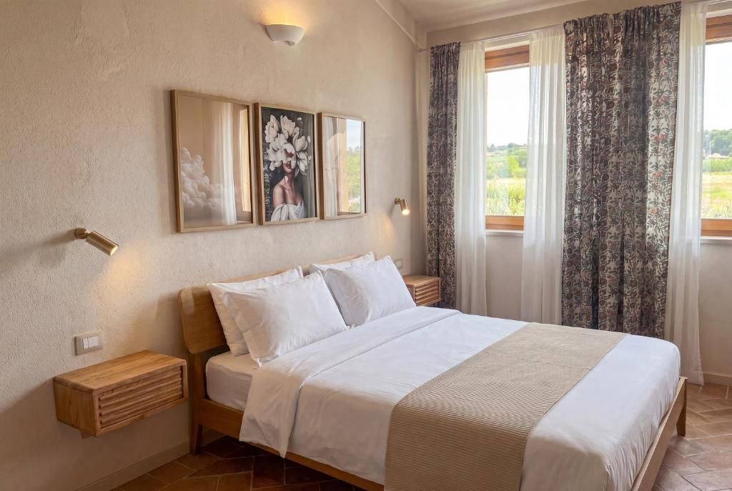 Une chambre à coucher avec un lit, des tables de chevet, un luminaire fixé au mur et une fenêtre avec des rideaux.