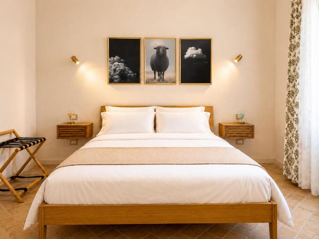 A bedroom with a wooden bed, white bedding, and three framed pictures on the wall.