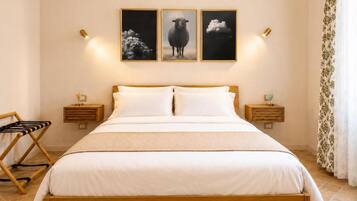 A bedroom with a wooden bed, white bedding, and three framed pictures on the wall.