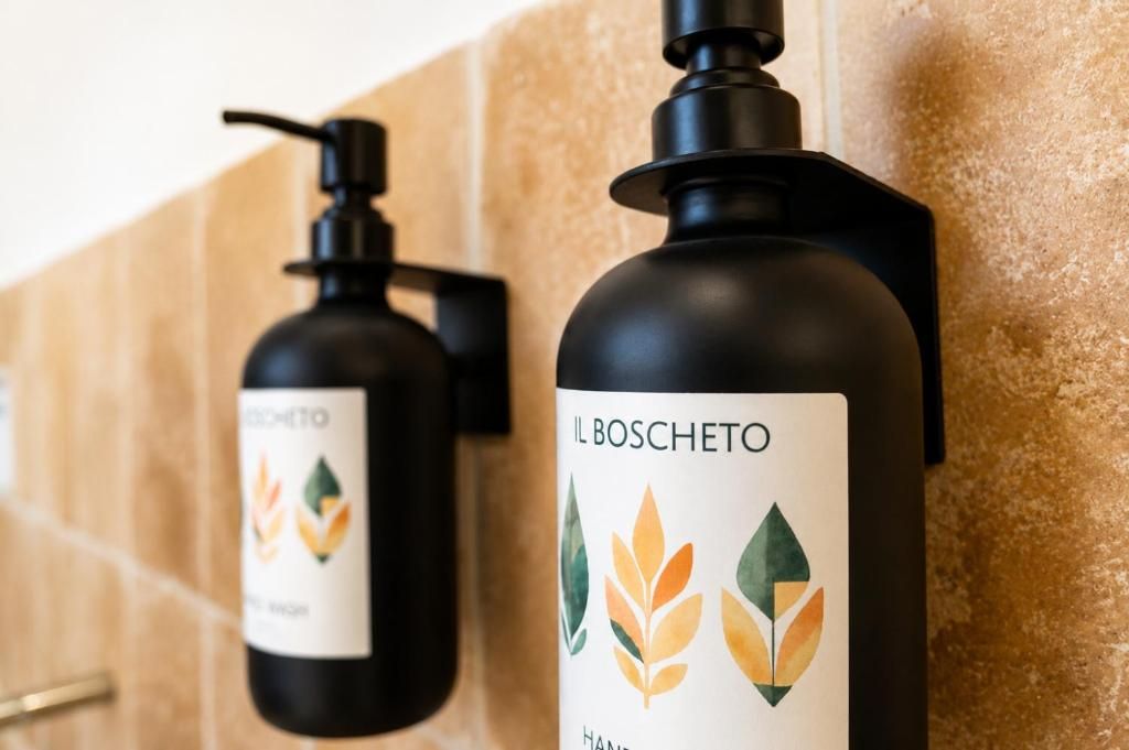 Two black bottles with pump dispensers, labeled 'IL BOSCHETTO,' against a tiled wall.