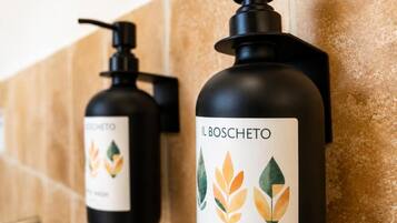 Two black bottles with pump dispensers, labeled 'IL BOSCHETTO,' against a tiled wall.