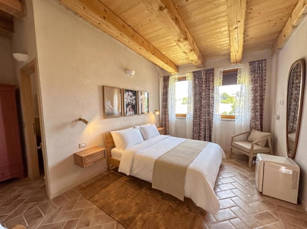 A bedroom with a bed, bedside tables, a chair, a mirror, and a heater.