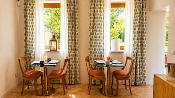 A dining area with two tables, chairs, and curtains.
