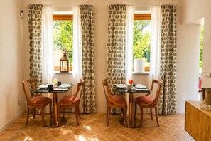 Un comedor con dos mesas, sillas y cortinas.