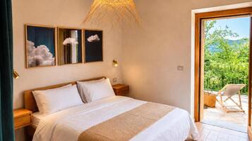 A bedroom with a bed, bedside tables, and a view of the outdoors.