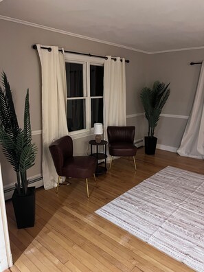 A room with two leather armchairs, a small side table, a potted plant, a patterned rug, and a window with curtains. - Charming Waterville Home on Quiet Street. Fully Furnished (Waterville)
