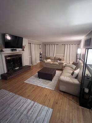 A living room with a fireplace, a television, a sofa, and a coffee table. - Charming Waterville Home on Quiet Street. Fully Furnished (Waterville)