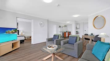 Een moderne woonkamer met een flatscreen televisie, een glazen salontafel en een bank.