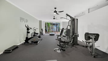 A gym with various exercise equipment, a ceiling fan, and a wall-mounted sign.