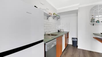 Une cuisine moderne avec des meubles blancs, un lave-vaisselle et un plan de travail.