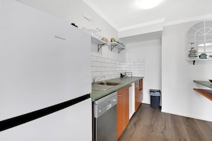 A modern kitchen with white cabinetry, a dishwasher, and a countertop. - Deluxe Views At Sovereign (Surfers Paradise)