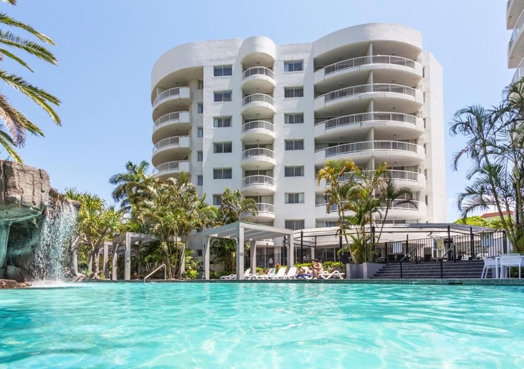 Un hôtel doté d’une piscine, de plusieurs balcons et d’une cascade décorative.
