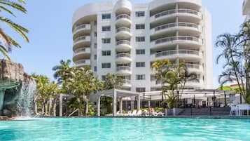 Un hôtel doté d’une piscine, de plusieurs balcons et d’une cascade décorative.