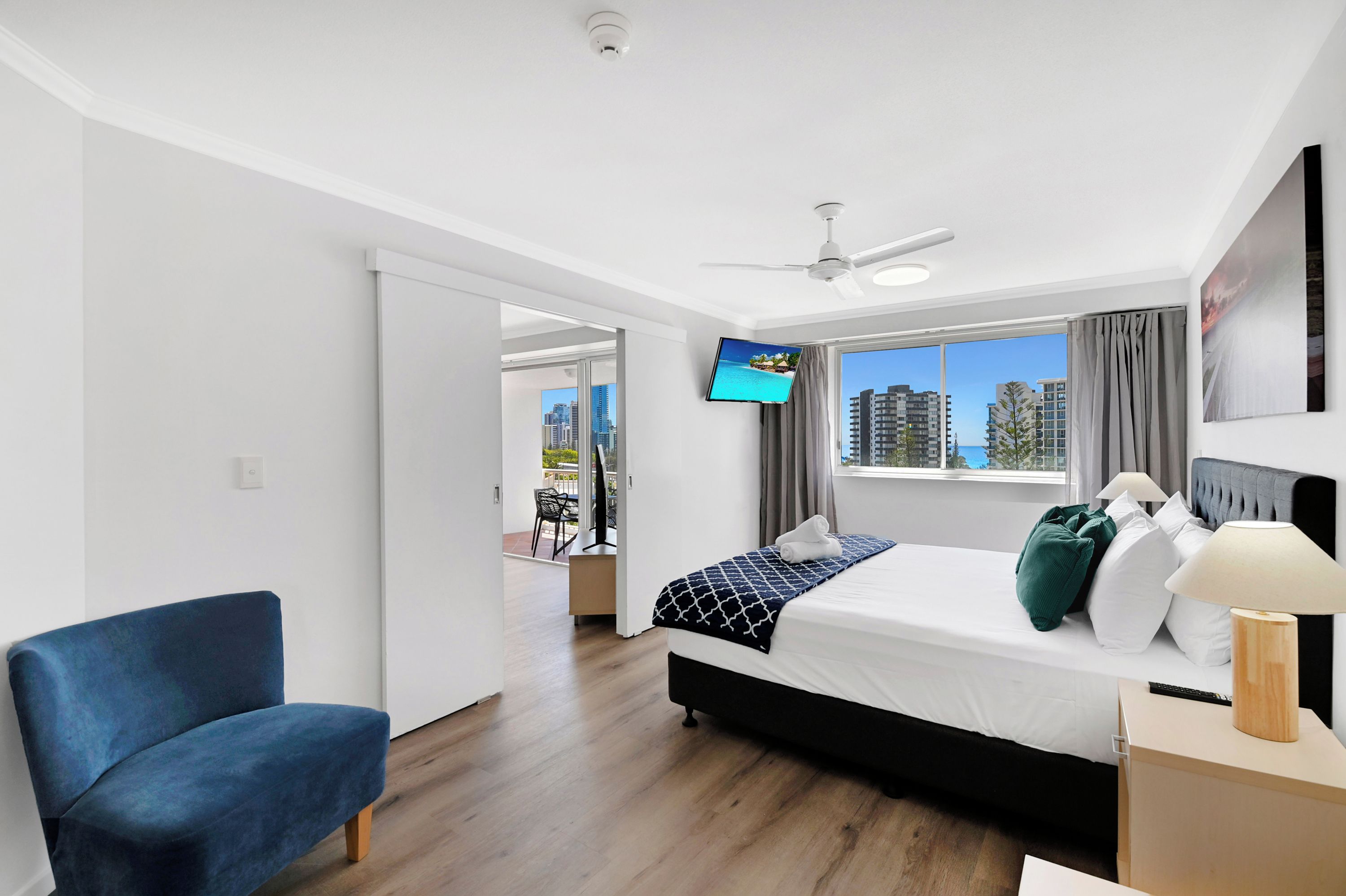 Habitación de hotel moderna con cama, escritorio, silla, televisor y vista a la ciudad.