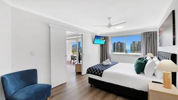 Habitación de hotel moderna con cama, escritorio, silla, televisor y vista a la ciudad.