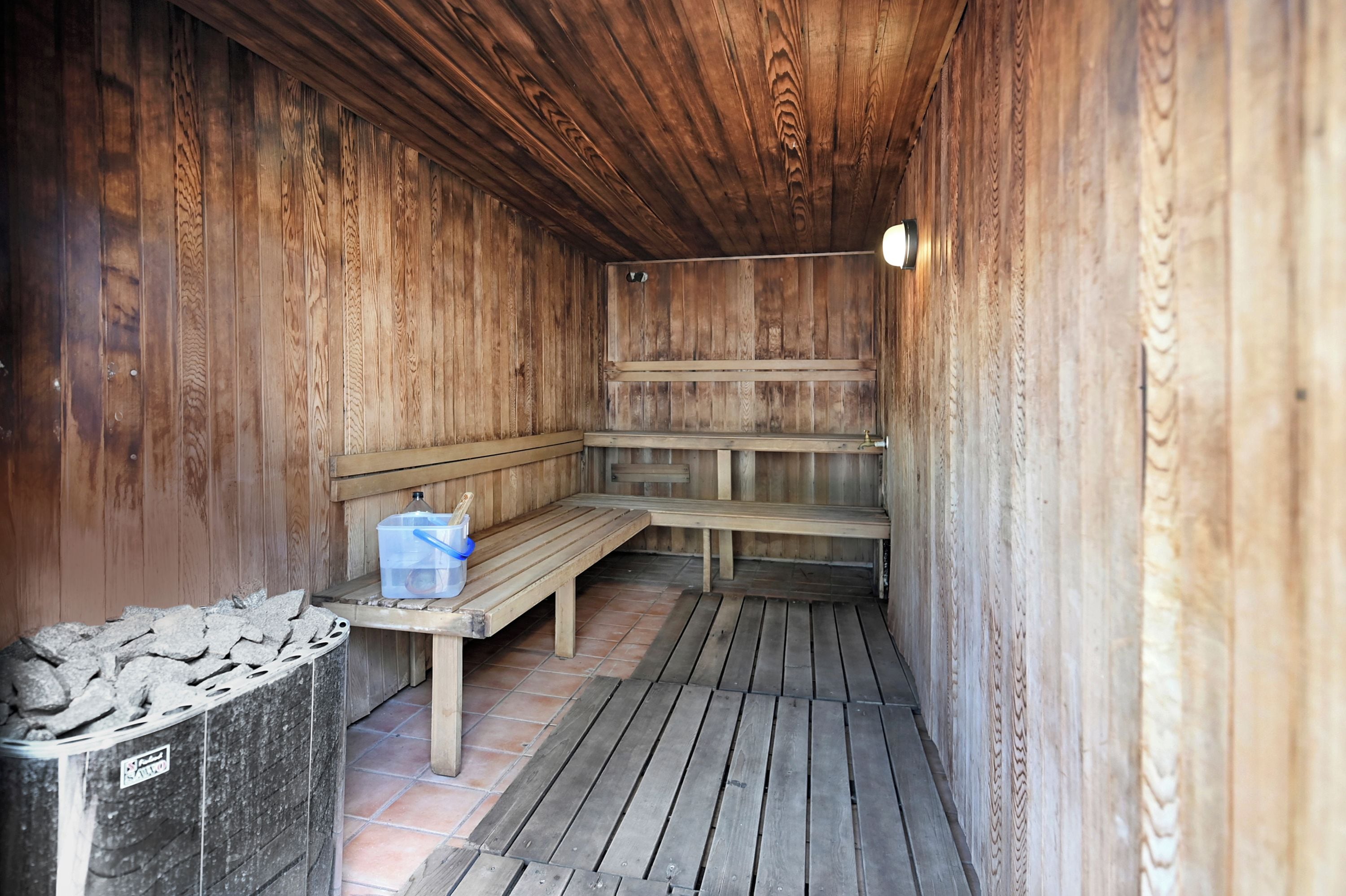 Una sauna de madera con bancos y un banco con un recipiente de objetos.