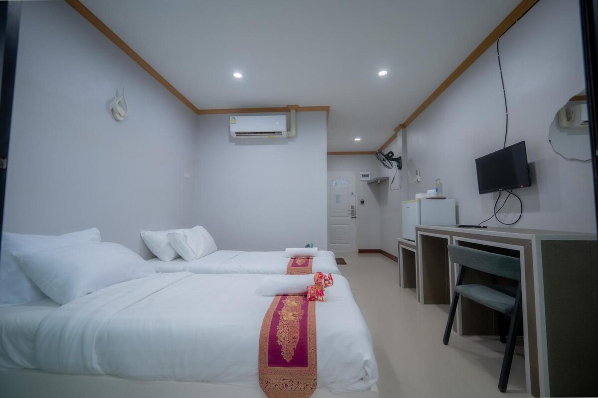 Una habitación de hotel con dos camas, un escritorio, una televisión y un aire acondicionado.