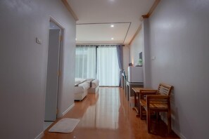 Un pasillo con una cama, una mesa de comedor con sillas y un refrigerador.