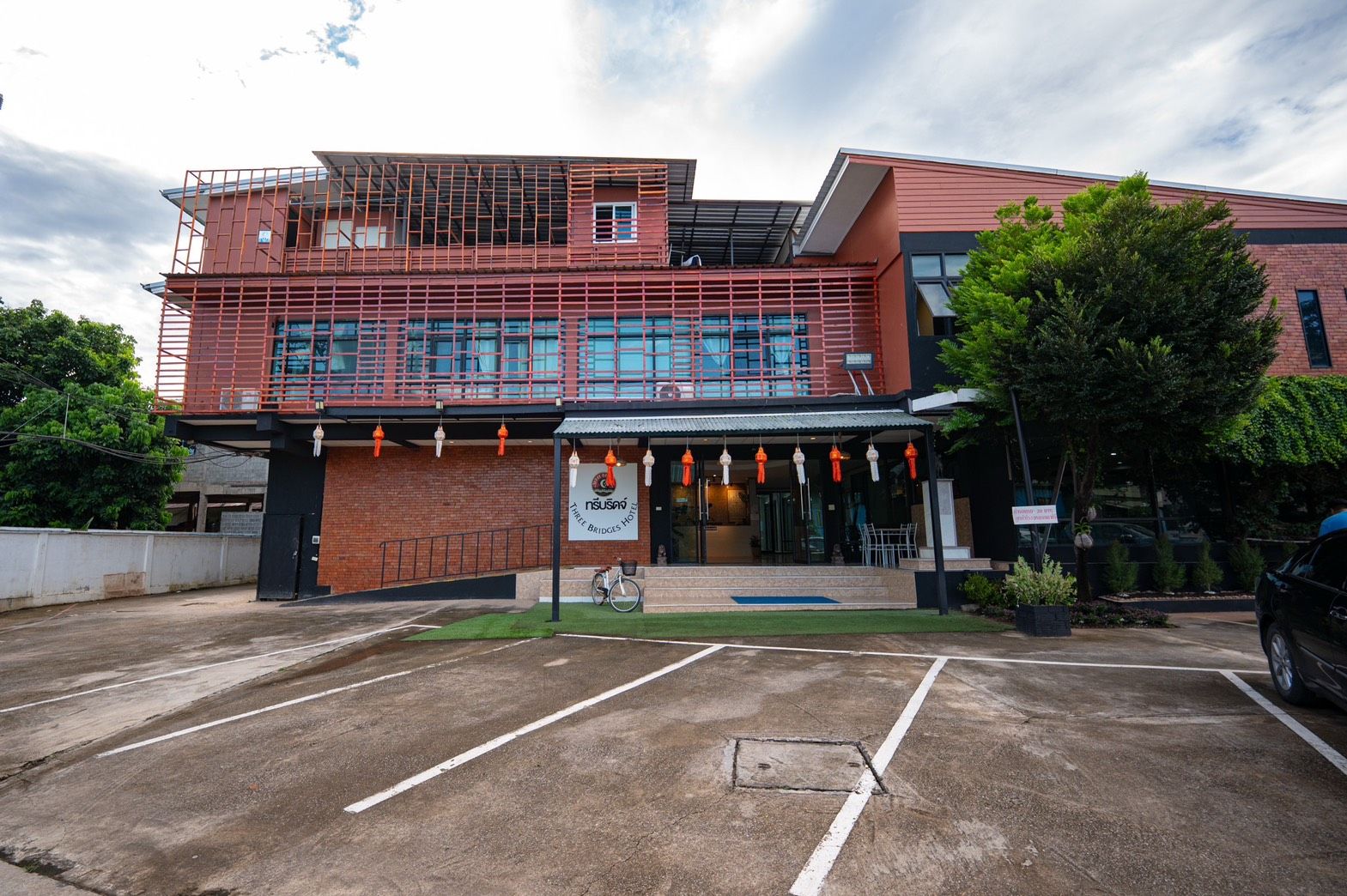 Un hôtel avec une façade en briques, une entrée couverte et un parking.