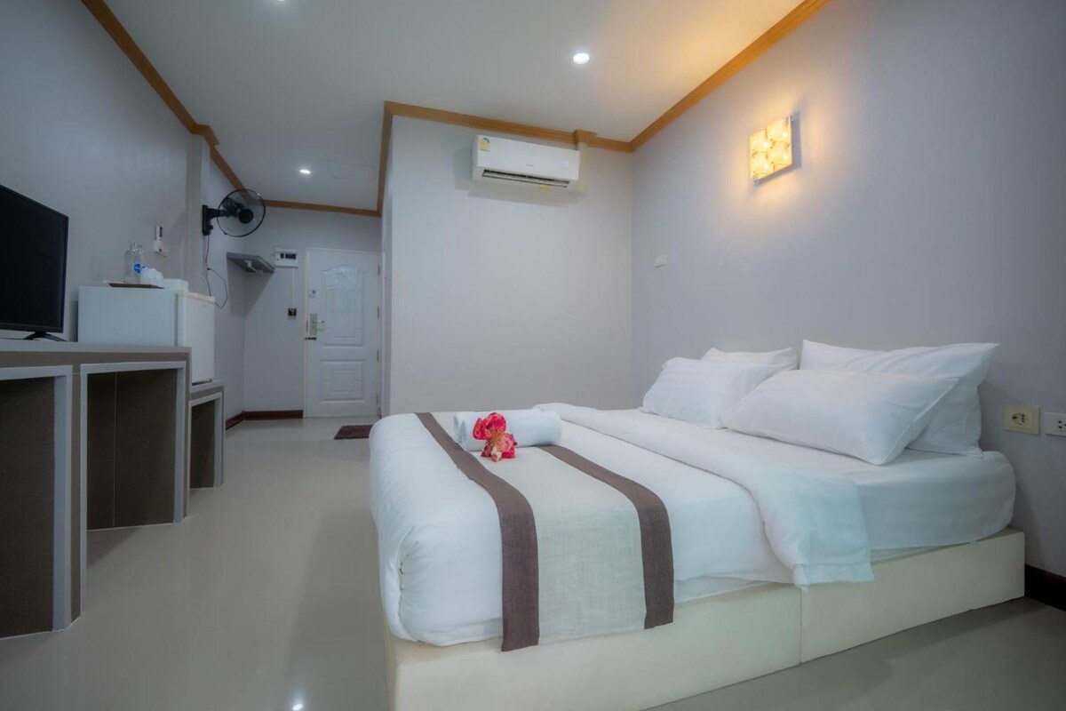 Una habitación de hotel con una cama, un escritorio, un televisor y un aire acondicionado.