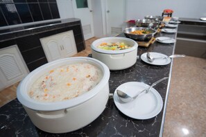 Montaje de bufé con grandes recipientes de comida, utensilios para servir y una encimera de mármol.