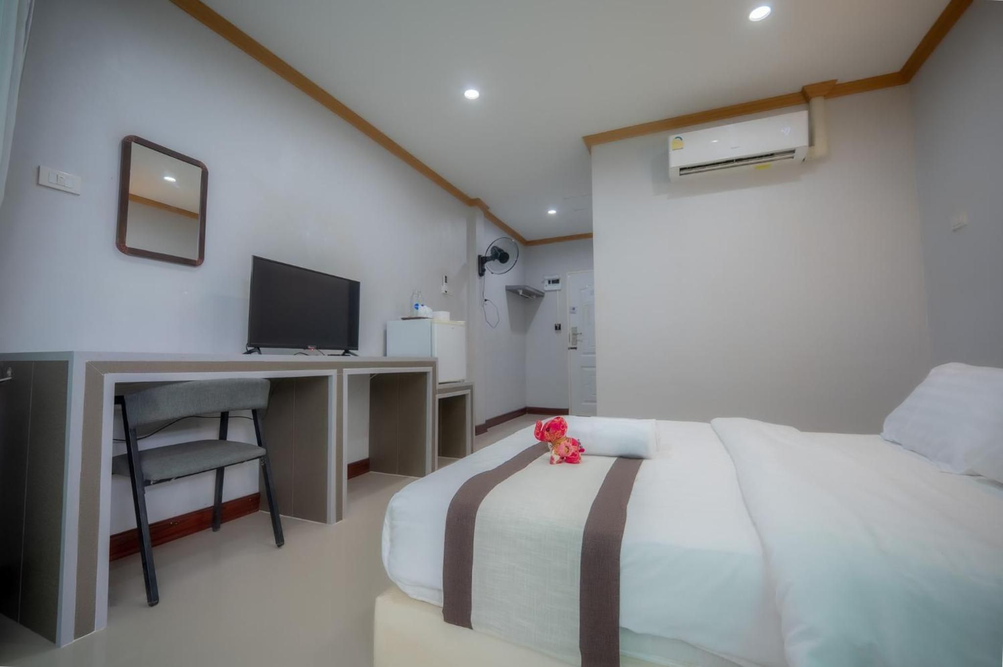 Una habitación de hotel con cama, escritorio, televisor y aire acondicionado.