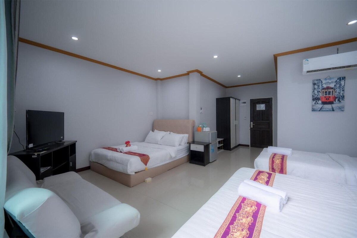 Una habitación de hotel con una cama, un escritorio, una silla, un televisor y un cuadro en la pared.