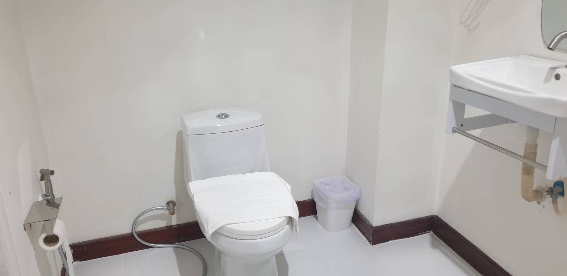 Uma casa de banho pequena com sanita, lavatório e um contentor de lixo.