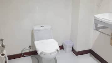 Uma casa de banho pequena com sanita, lavatório e um contentor de lixo.