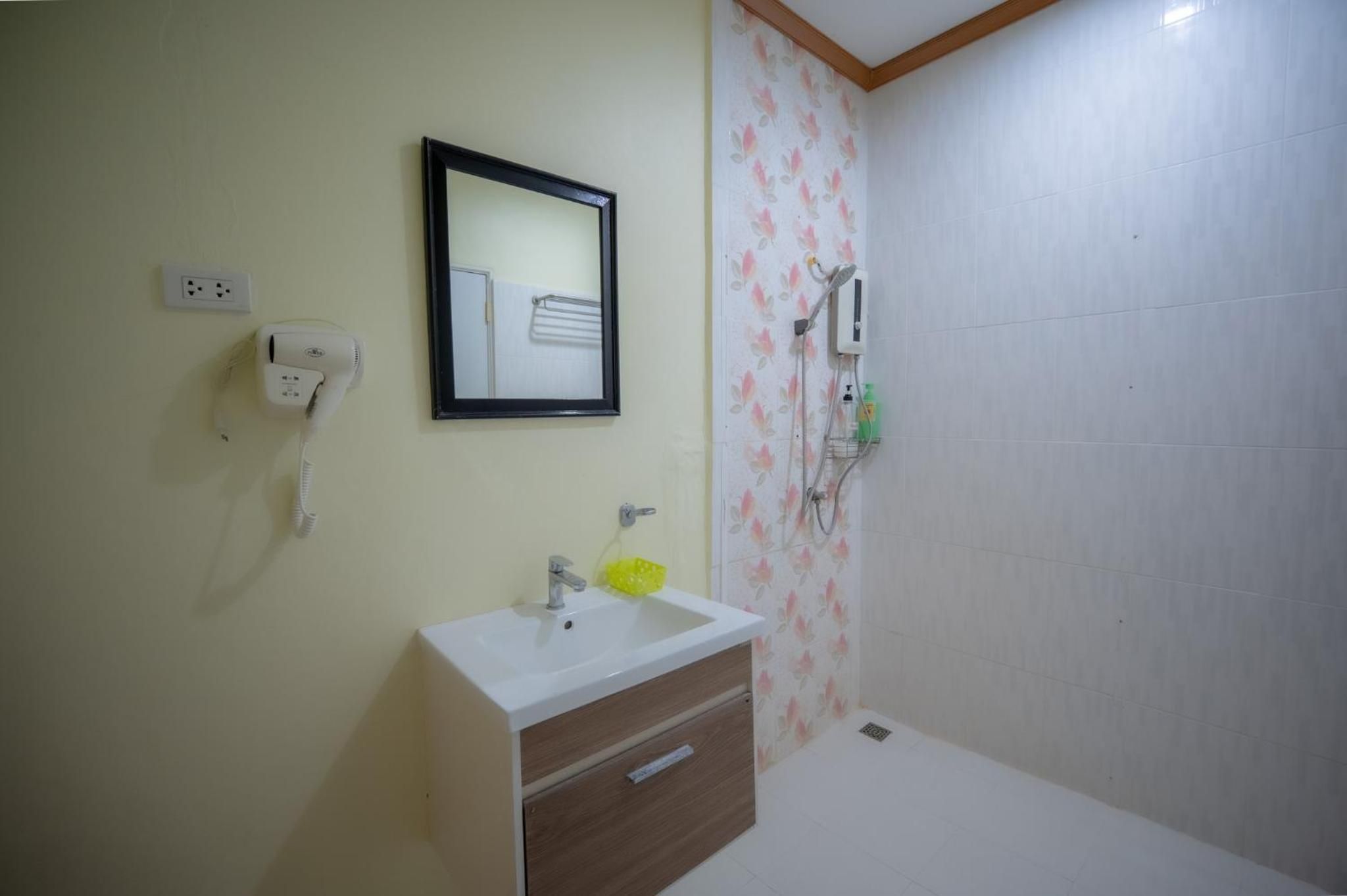 A bathroom with a sink, mirror, and shower.