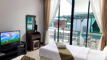 Una habitación de hotel con dos camas, televisor, escritorio y balcón con vistas.