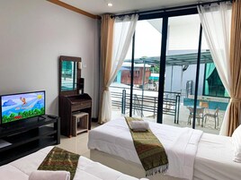 Una habitación de hotel con dos camas, televisor, escritorio y balcón con vistas.