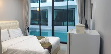 Habitación de hotel con una cama, un escritorio y vistas a una piscina.