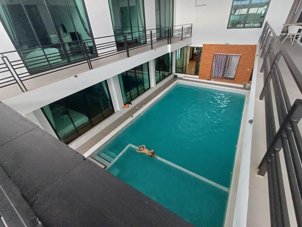 An indoor swimming pool with a clear view of the surrounding area, including a balcony and a brick wall.