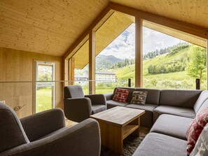 A cozy room with a wooden ceiling, large windows, a sofa, and a coffee table. - One-bedroom Cabin (Sankt Georgen am Kreischberg)