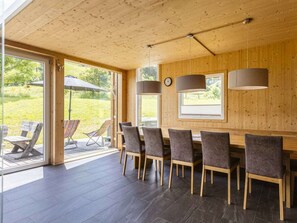 A wooden interior with a dining area, large windows, and a view of the outdoors. - One-bedroom Cabin (Sankt Georgen am Kreischberg)