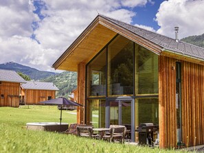 A wooden cabin with large windows, outdoor seating, and a view of the surrounding landscape. - One-bedroom Cabin (Sankt Georgen am Kreischberg)
