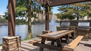 Eine Außenpatio mit einer Steinsäule, einem Holztisch und einem Grill.
