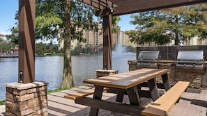 Une terrasse extérieure avec un mur en pierre, une table en bois et un barbecue.