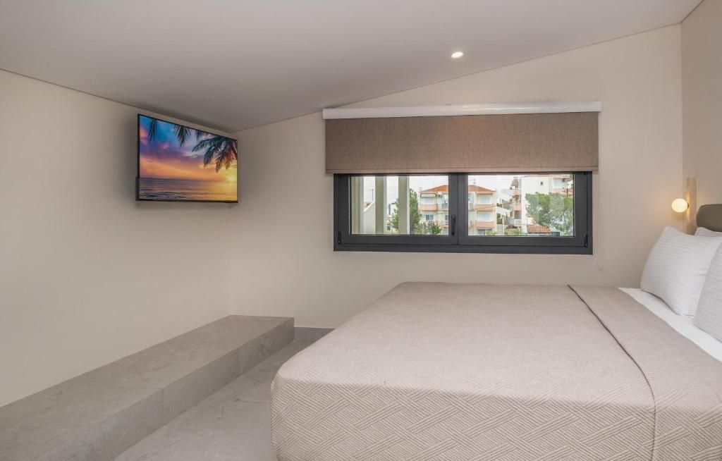 Un dormitorio con cama, ventana con vistas a edificios, un cuadro de un atardecer y una lámpara.