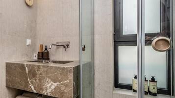 Baño con lavamanos de mármol, toallero y ventana con puerta de vidrio esmerilado.
