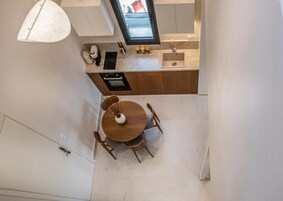 A modern kitchen with a dining area, a built-in oven, and a window above the sink.