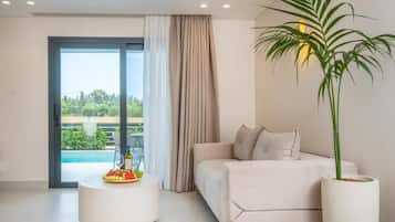 Una sala de estar moderna con un sofá, una mesa de centro redonda con una bandeja de frutas, una planta en maceta y vistas a una piscina a través de una puerta de cristal.