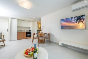 A modern living room with a dining area, a kitchen in the background, and a sunset painting on the wall. - Calista Horizon by Booking Kottas (Kallithea)