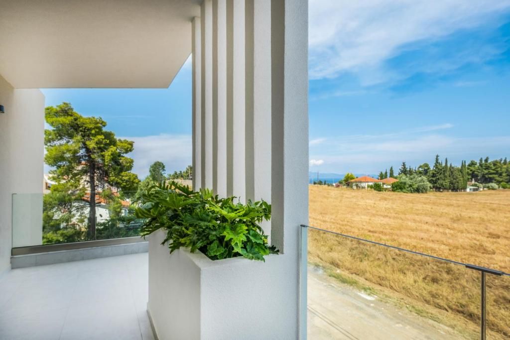Ein Balkon mit Blick auf ein Feld und entfernte Gebäude.