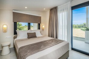 Quarto com cama grande, mesa de cabeceira, janela com cortinas e vista para o verde lá fora.