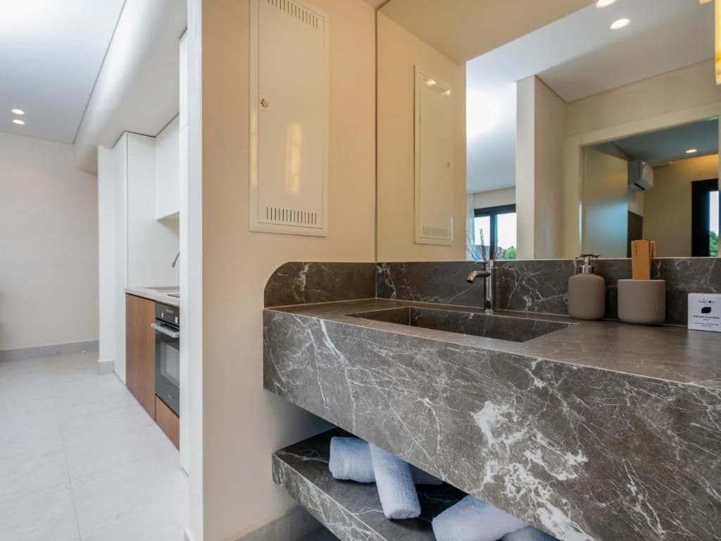 A modern bathroom with a marble sink, a large mirror, and built-in cabinets.