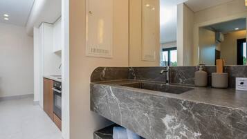 A modern bathroom with a marble sink, a large mirror, and built-in cabinets.